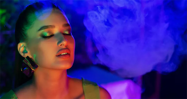 LIFEORIA A woman enjoys smoking a cigarette amidst colorful lights, embracing the vibrant LIFEORIA.